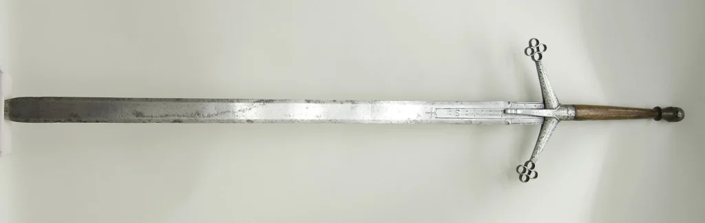 Historical two-handed claymore sword with a wooden grip and ringed cross-guard, displayed against a white background.