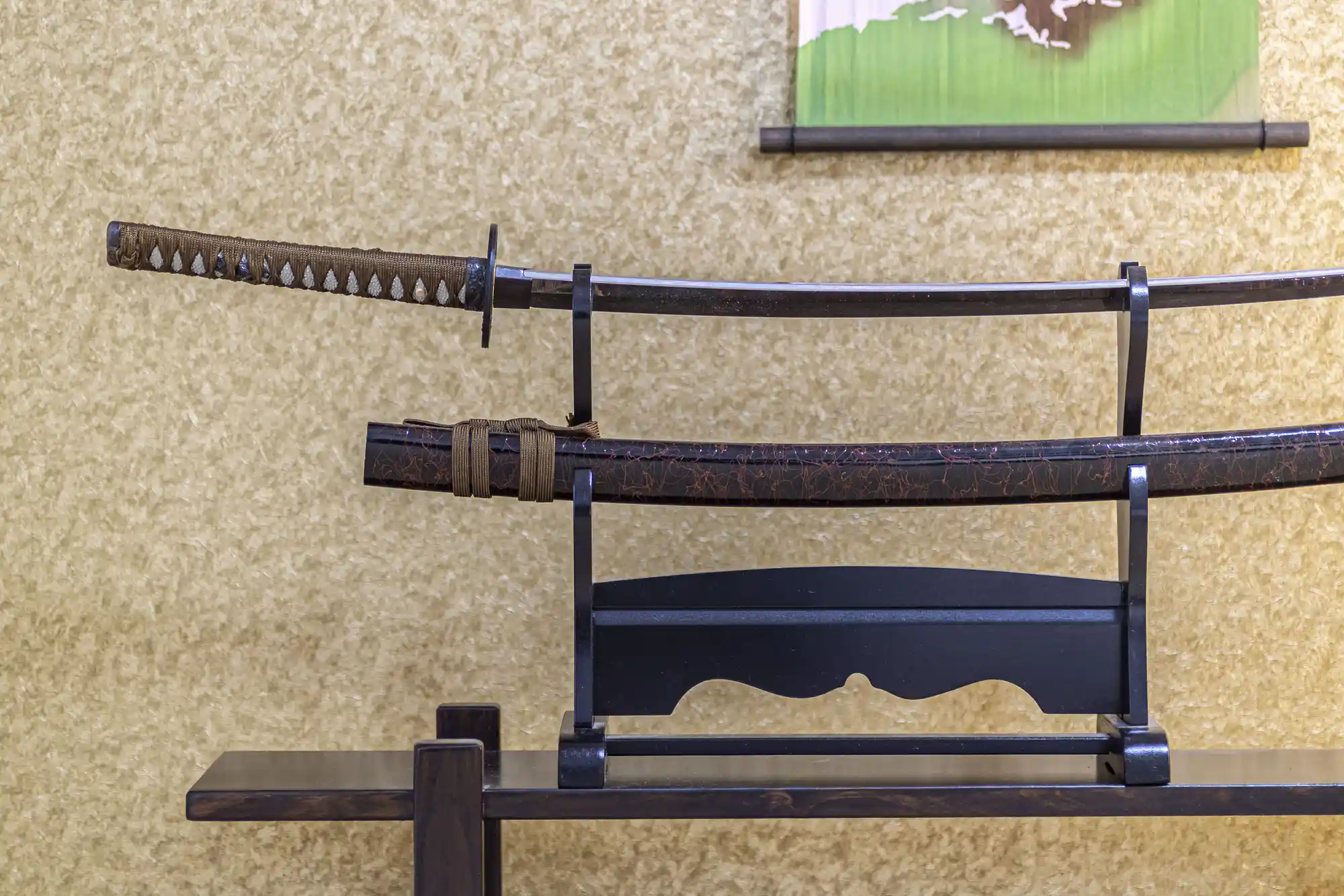 A katana displayed with the blade outside the scabbard in a sword stand display.