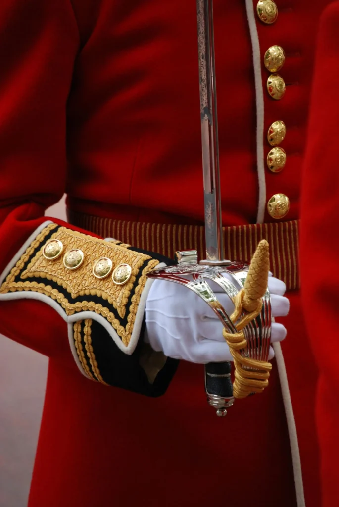 Military officer in red uniform holding a sabre, symbolizing authority and tradition.