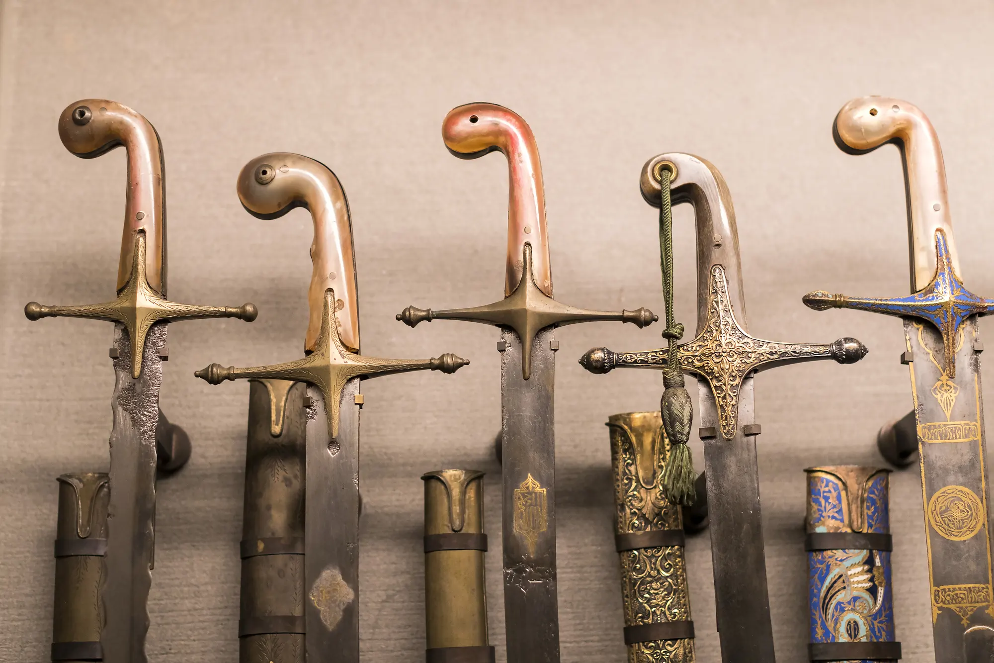 Turkish sabre swords hanging on a wall, featuring curved blades and decorative handles.