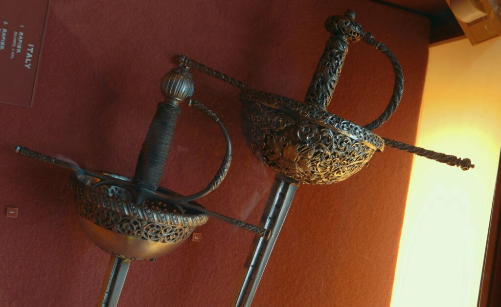 Two ornate Italian rapiers with intricate cup hilts and detailed grips.