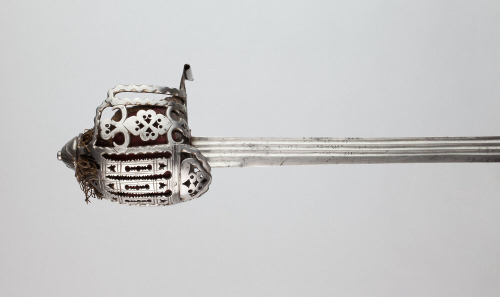 Close-up of a decorative basket-hilted sword with intricate designs, isolated on a grey background.