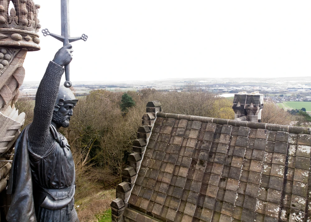 Statue of William Wallace holding a sword aloft on a castle tower.