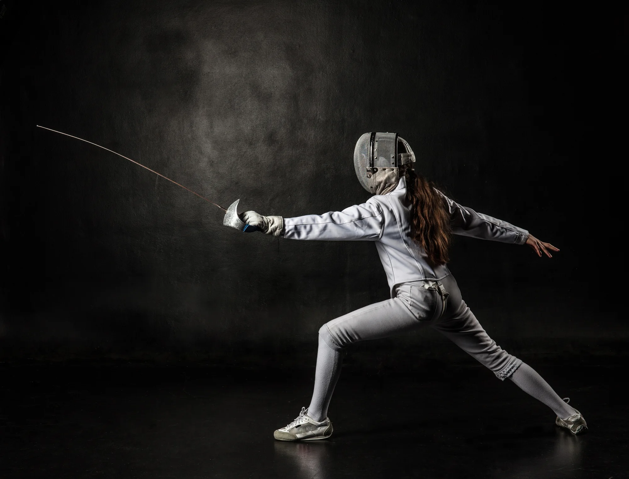 A girl with fencing costume and a fencing sabre.