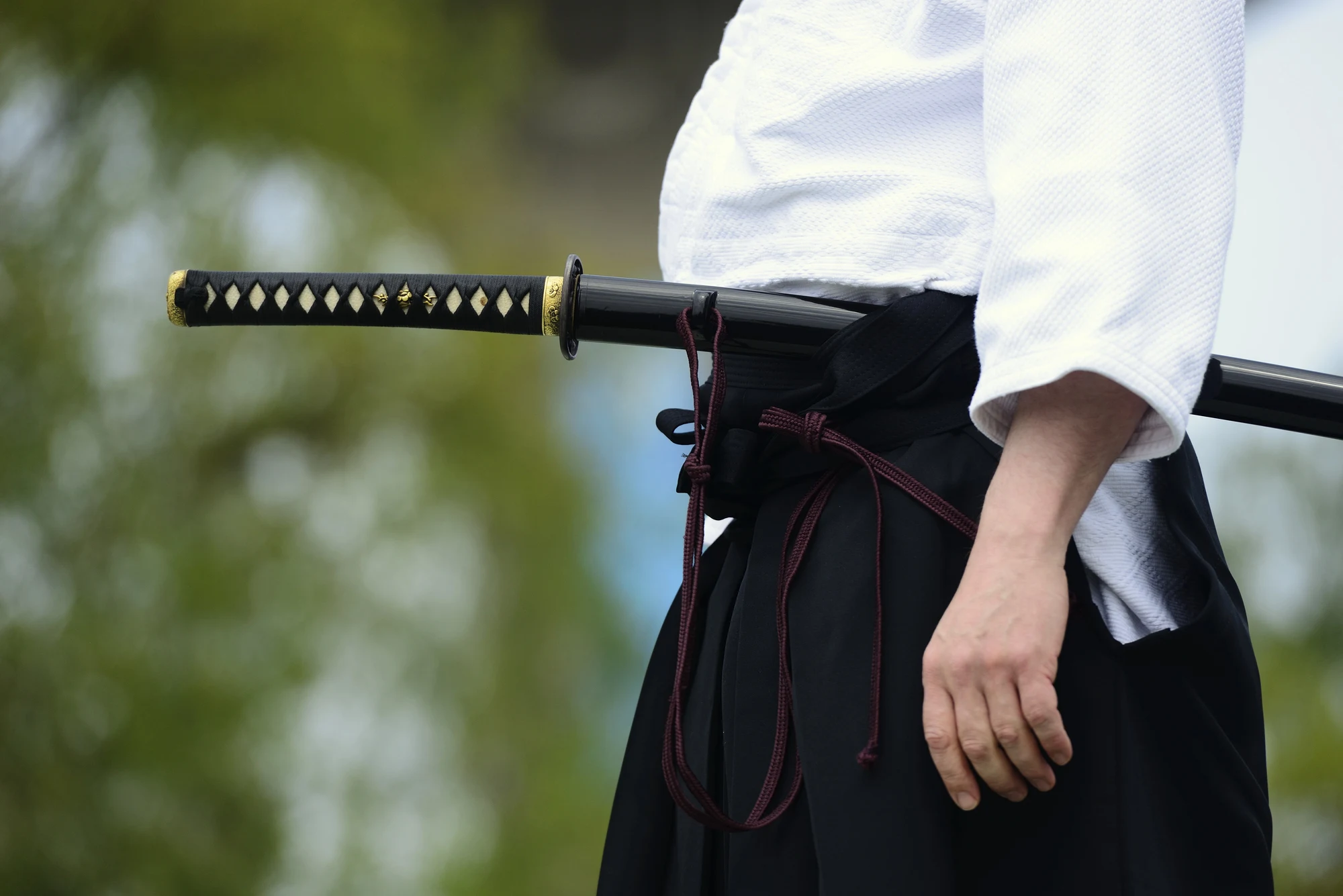 Man with a katana worn blade-up at his side.