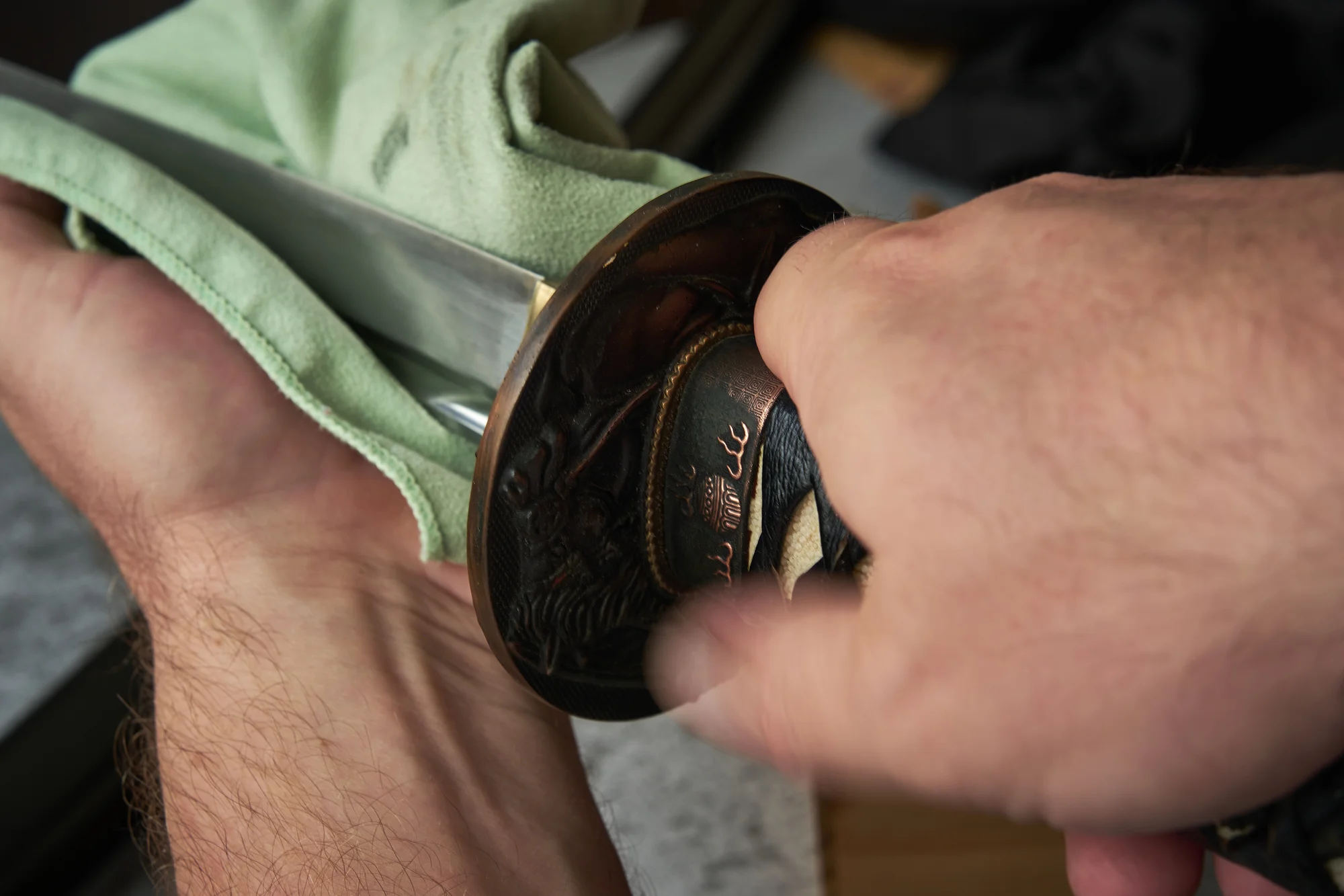 Demonstrating how to clean a katana by wiping the blade with a soft cloth.