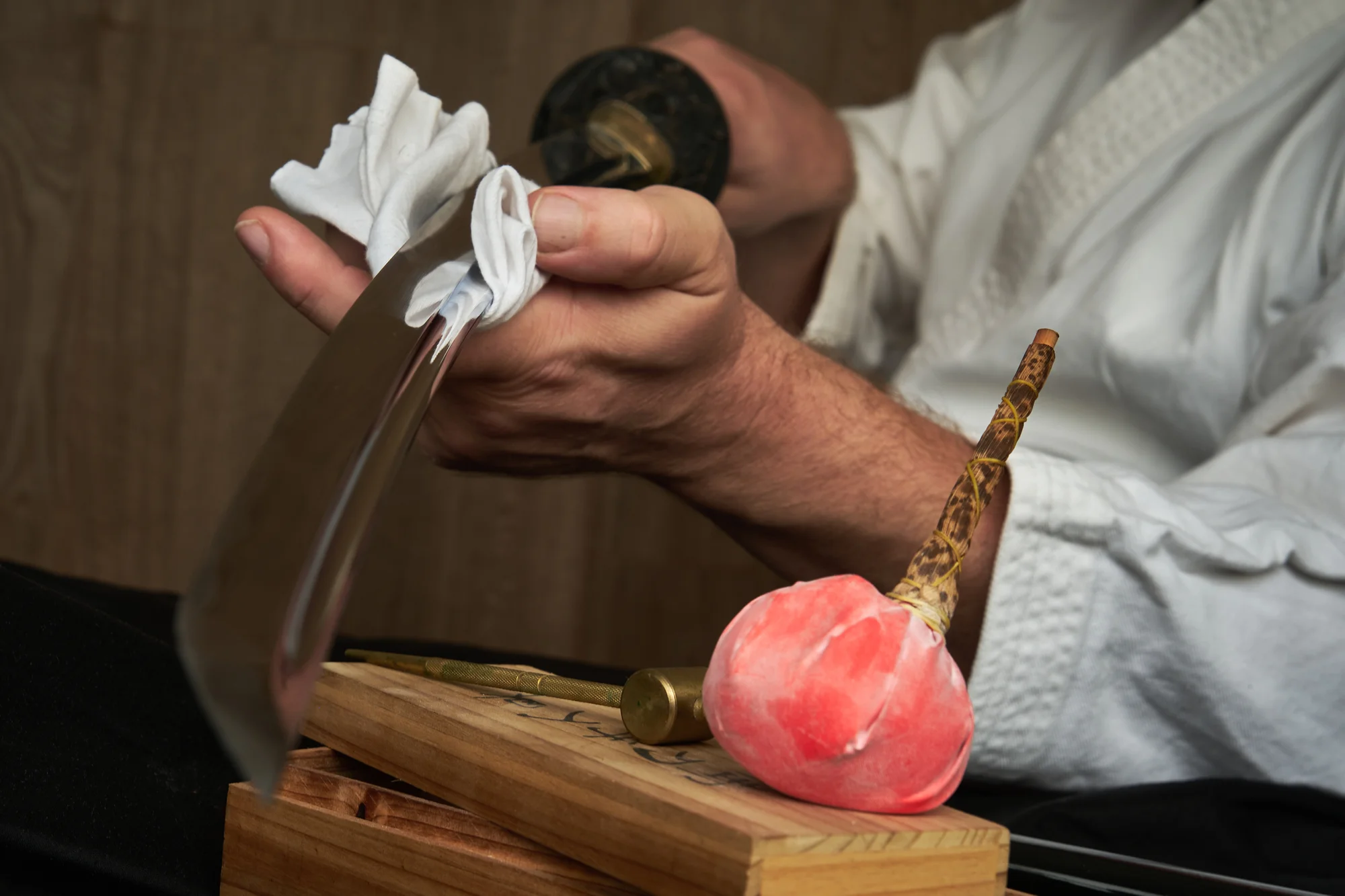 Cleaning a katana blade with a cloth after applying uchiko powder.