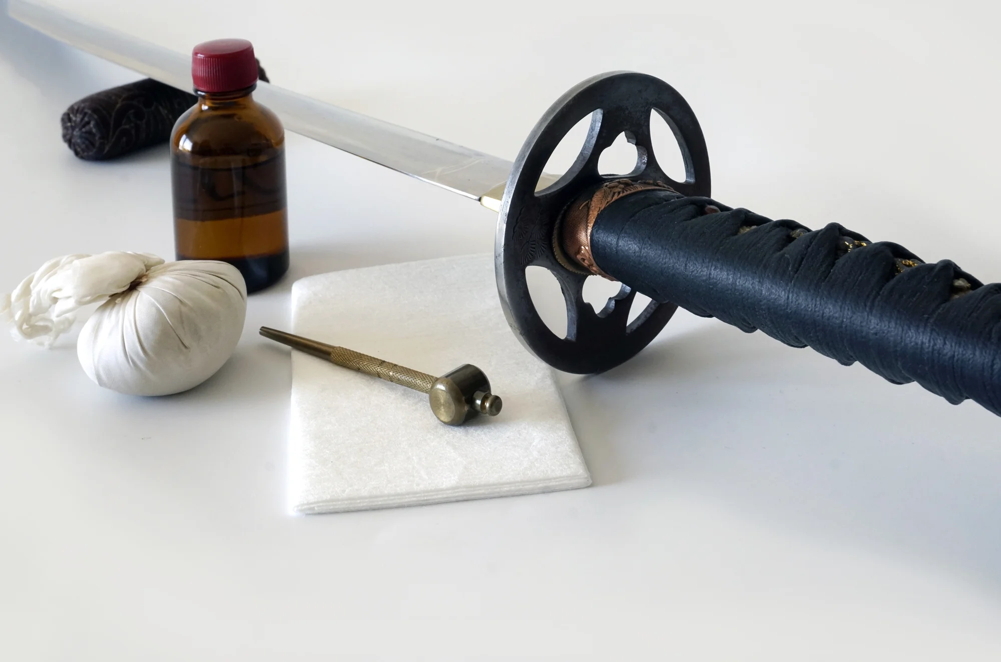 Katana maintenance kit, uchiko powder ball, oil bottle, mekugi-nuki tool, and cleaning cloth.