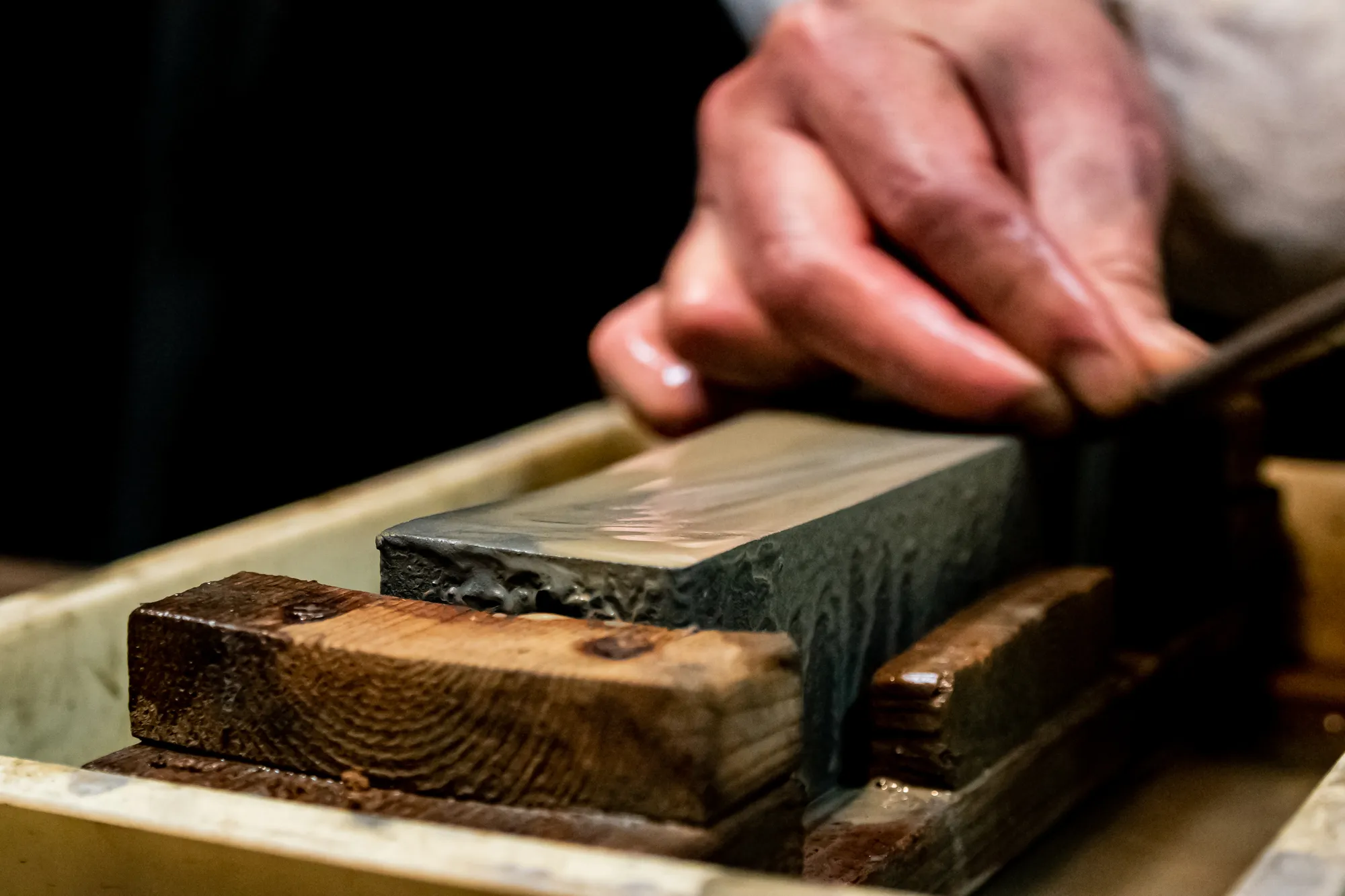 Sharpening a katana blade on a whetstone, with water on the stone for lubrication.