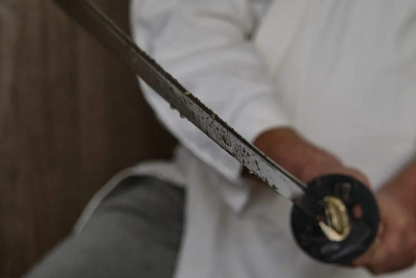 A person holding a rusted katana blade.