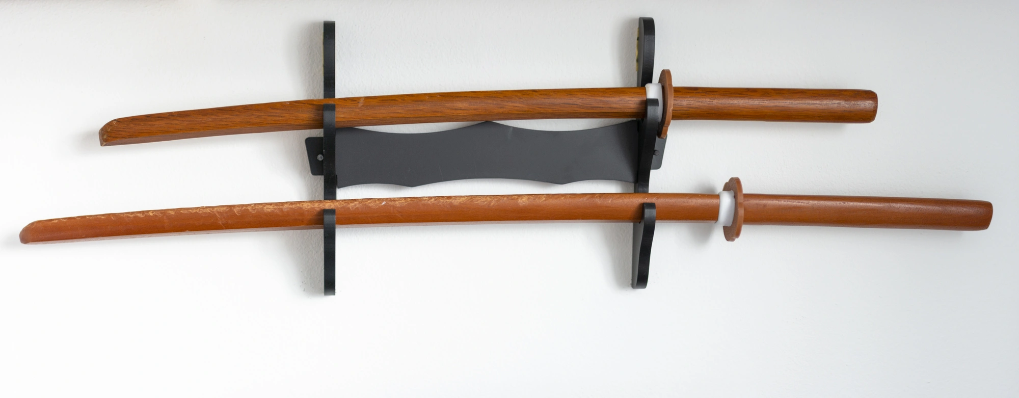 Two wooden katanas displayed in a wall mount.